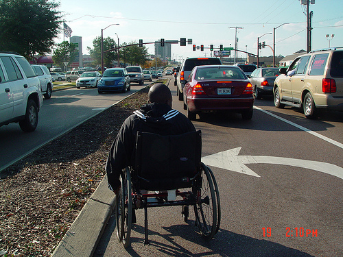 A wheelchair user struggles to navigate a wide road. Research indicates that street design plays a significant role in the crash rates on our roads. Photo: Transportation for America