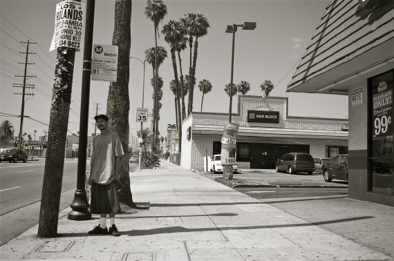 A man waits for a bus in the shade of a telephone pole on Figueroa Ave., just north of 85th St. There tends to be fewer shelters and less shade available to those who are most heavily dependent on transit. Sahra Sulaiman/Streetsblog L.A.
