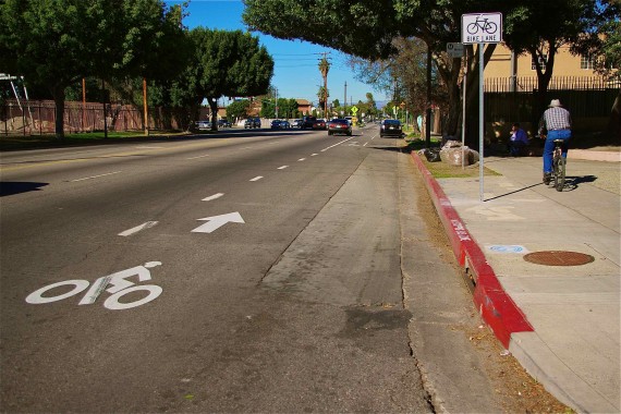 A man cycles along the sidewalk next to a bike lane at 96th and Central in Watts to avoid cars speeding their way toward Hooper. Sahra Sulaiman/Streetsblog L.A.