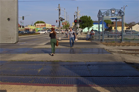 Pedestrians cross the Union Pacific tracks at Vernon, even as a Blue Line train approaches. Meanwhile, the cyclist remains behind the pedestrian barrier. Sahra Sulaiman/Streetsblog L.A.