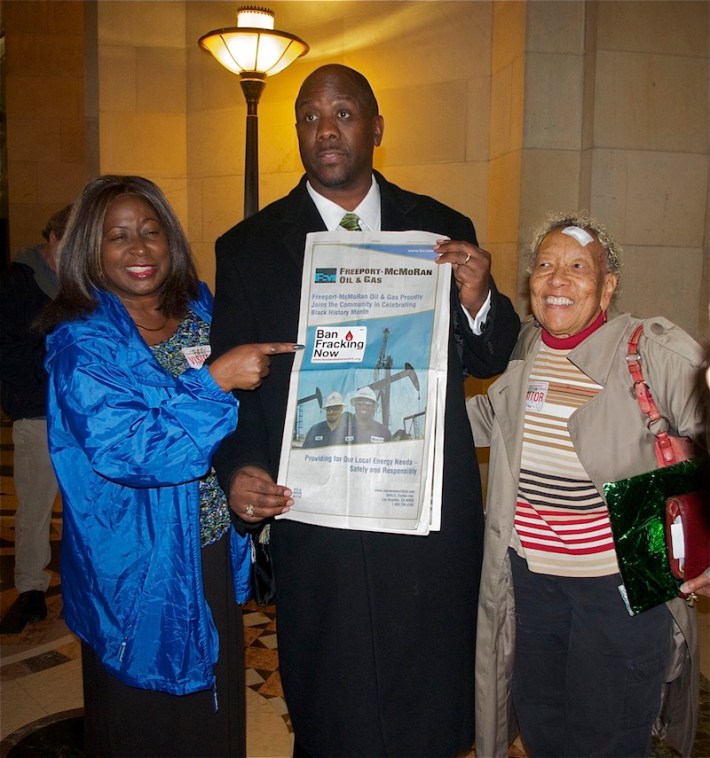 Pastor Kevin Sauls and members of Holman Church place a Ban Fracking Now sticker on the full page ad Freeport McMoRan Oil & Gas took out in the LA Sentinel in anticipation of the City Council vote. Sahra Sulaiman/LA Streetsblog