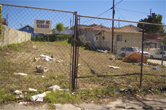 Trash accumulates in a vacant lot where dumping is discouraged by a sign. Sahra Sulaiman/LA Streetsblog