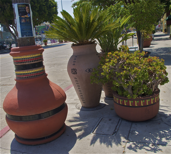 Planters, thatch-wrapped poles, and hanging planters (out of frame) that grace Degnan and other streets in Leimert Park Village.