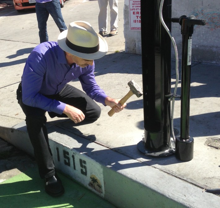 Councilmember Mitch O'Farrell hammers in the final pin to secure the new bike repair stand at Sunset Triangle Park Plaza