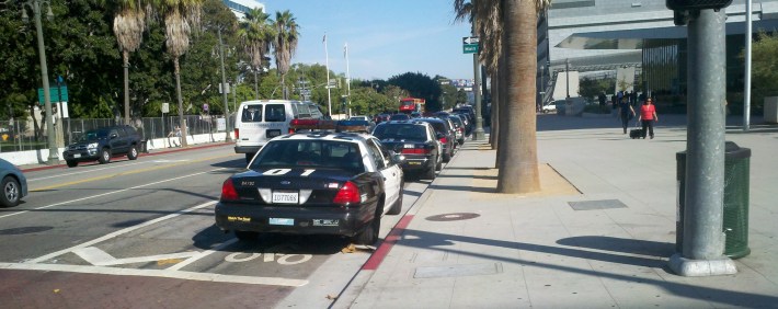 LAPD protects the bike lane in front of headquarters from sun and rain elements that could damage the paint job. Police cars parked in the bike lane, First Street between Spring and Main in downtown L.A.