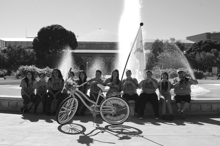 Members of the Sisterhood Pack (a subset within the club) take a break from the Cancer Awareness ride to pose with the bike they collaborated to build. The bike sports a flag listing the names of cancer victims from the community. Sahra Sulaiman/Streetsblog L.A.