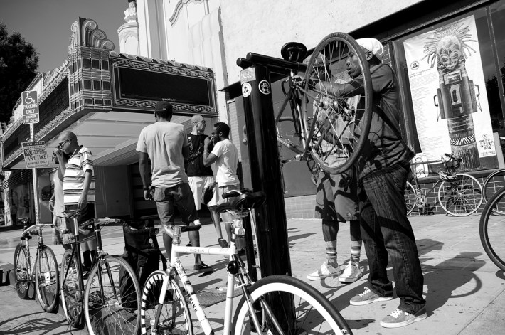 Ade Neff works on his bike in front of the Vision Theater in Leimert Park. Sahra Sulaiman/Streetsblog L.A.