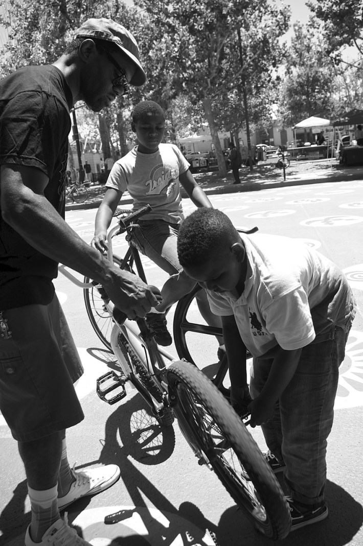 Jeremy Swift teaches the boy to work on his bike while Cortez Wright watches. Sahra Sulaiman/Streetsblog L.A.