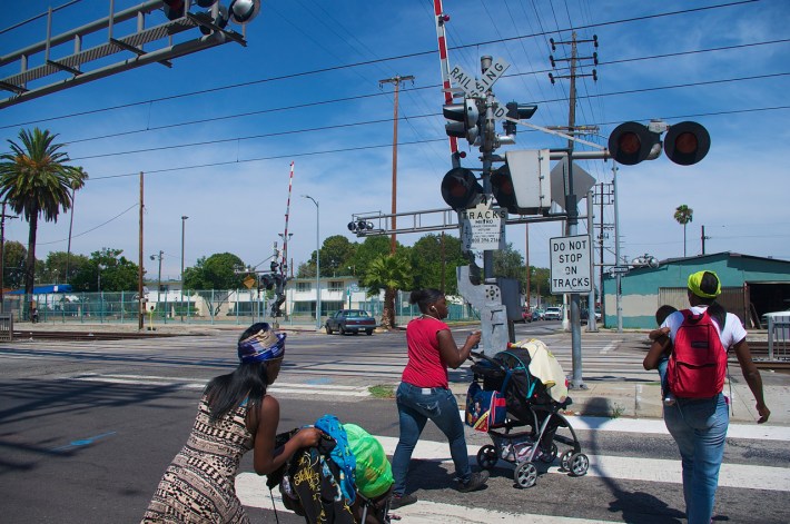 A family with small children moves across the tracks at 55th and Long Beach Ave. Sahra Sulaiman/Streetsblog L.A.