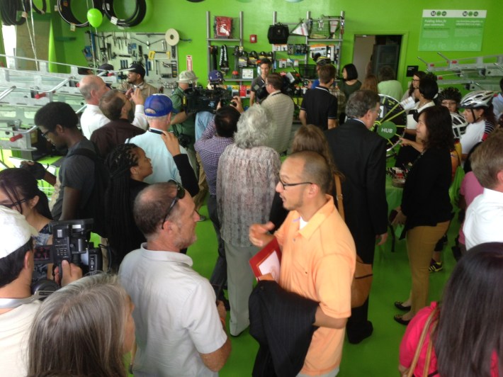 The interior of the hub - with cyclists, agency staff, elected officials and others celebrating. Center (in orange shirt) is Gene Oh, owner of BikeHub, the operators of the facility.