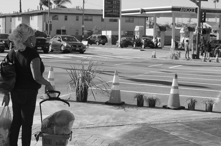 A woman eyes up the scramble crosswalk that could take her through the intersection much more efficiently than she could normally go--something that is appealing when you are carrying a lot of stuff with you. Sahra Sulaiman/Streetsblog L.A.