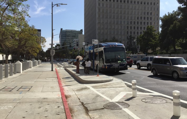 Passengers board a DASH bus at a Los Angeles Street's transit island