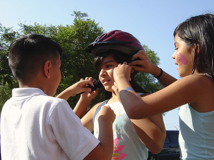 Kids practice putting on a helmet with tips they learned from Multicultural Communities for Mobility. Sahra Sulaiman/Streetsblog L.A.