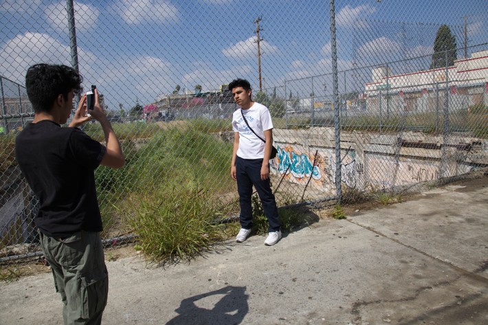 J.C. takes a photo of Miguel in front of graffiti found at Manchester/Vermont. Sahra Sulaiman/Streetsblog L.A.