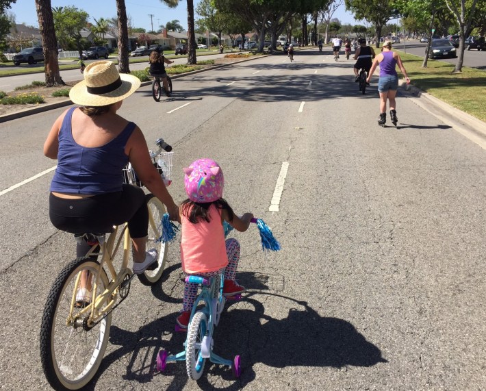 A mother assists her training-wheeled daughter at Beach Streets