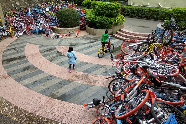 This picture taken on January 16, 2017 shows rented bicycles from bike-sharing firms near the entrance of Xiashan park in Shenzhen, Guangdong province. More than 500 bicycles from China's flourishing bike-sharing companies have been dumped in huge piles on the streets of the southern city of Shenzhen, reports said. / AFP / STR / China OUT (Photo credit should read STR/AFP/Getty Images)