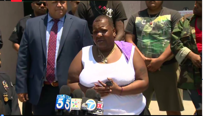 Frederick Frazier's mother, Beverly Owens, speaks during the press conference. Behind her stand Moses Williams and Keiven Muñoz, close friends of Frazier, and Detective Ryan Moreno (at left).