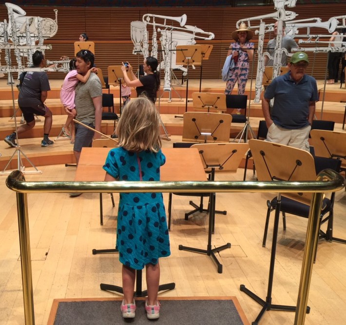 Streetsblog L.A. editor's daughter trying out the conductor's podium at Kiehl Johnson's art installation at Disney Hall