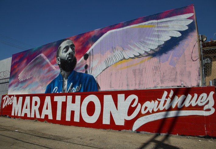 A portrait of Nipsey Hussle by artist Danny Mateo graces the alley adjacent to the strip mall where Hussle was killed at Crenshaw and Slauson on March 31. "The Marathon Continues" references both his approach to building his career from the ground up and his understanding of what it took to bring the community along with him. Sahra Sulaiman/Streetsblog L.A.