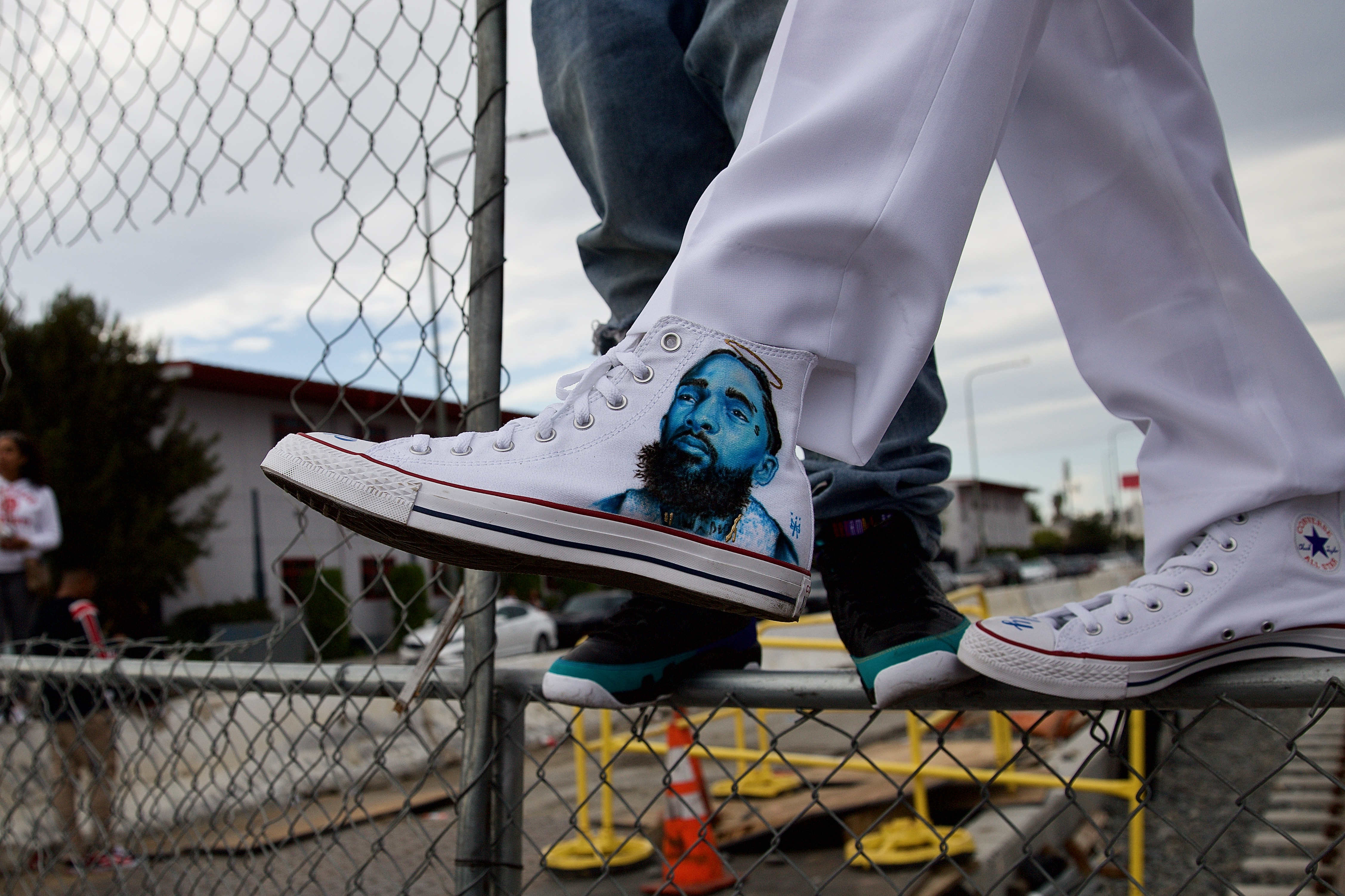 Jermaine Welch shows off the shoe he had custom painted in Nipsey Hussle's honor while waiting for Hussle's funeral procession to pass through the intersection at Crenshaw and Slauson on April 11. Hussle was killed in front of his store, The Marathon, on March 31. Sahra Sulaiman/Streetsblog L.A.