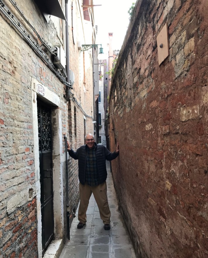 Streetsblog editor Joe Linton touching both sides of a walk street in Venice, Italy