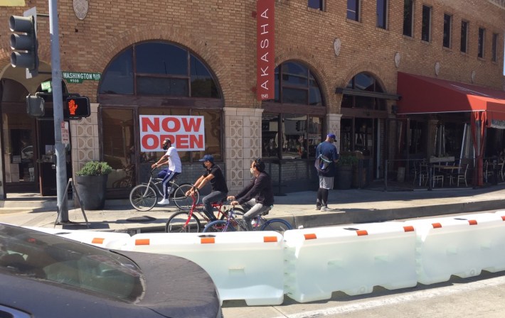 Cyclists are allowed in the bus lane, though many are on sidewalks and in space behind barriers