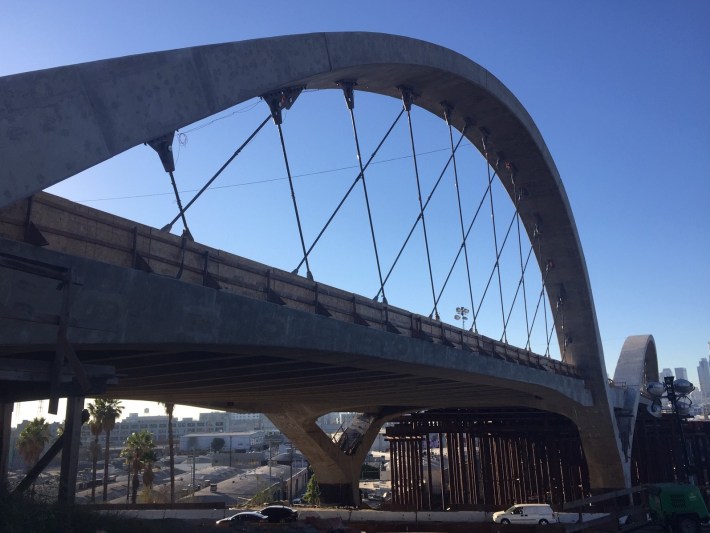 The viaduct's completed concrete arches include crisscrossed cable stays