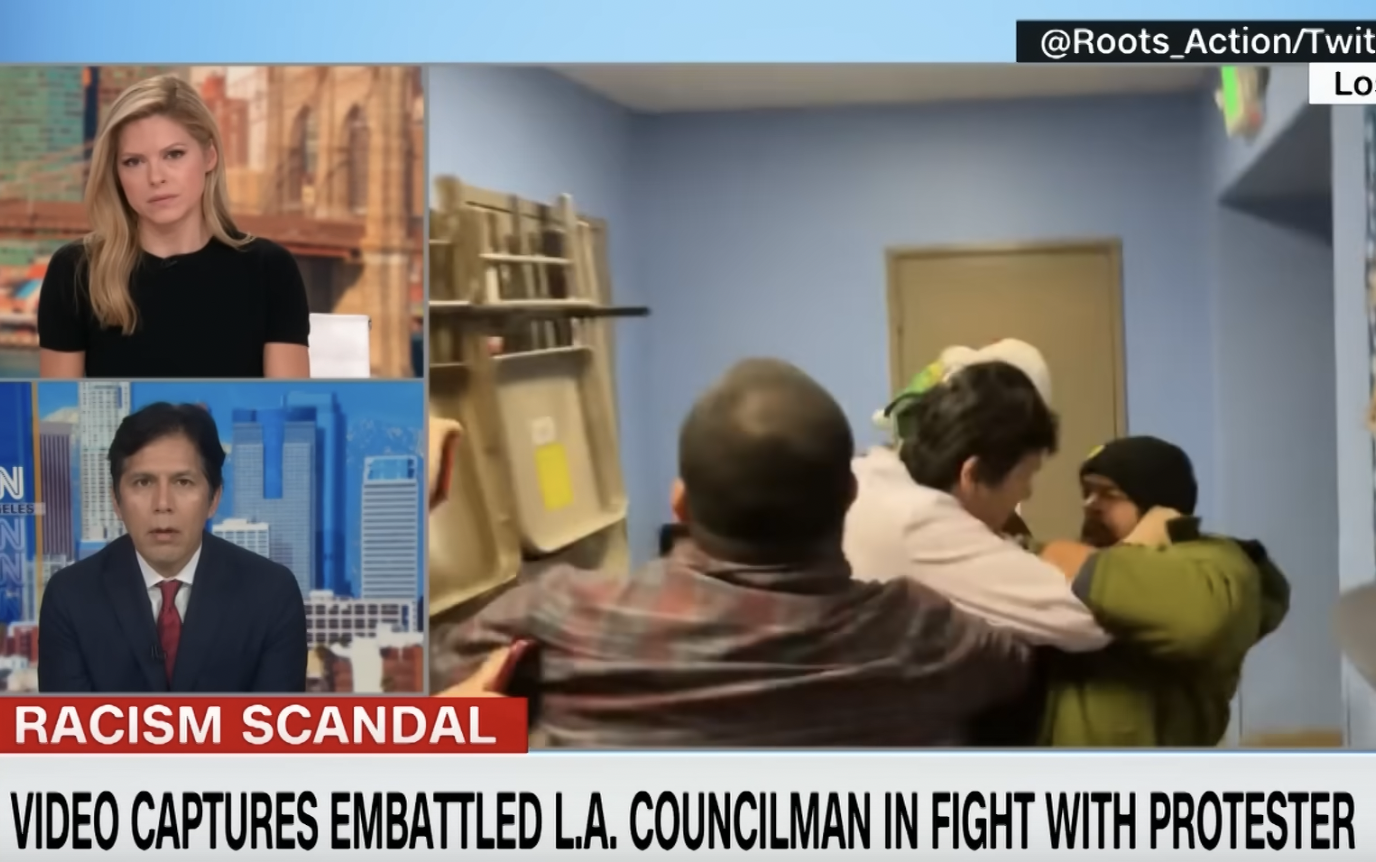 Disgraced L.A. City Councilmember Kevin de León speaks to CNN's Kate Bolduan. Footage of his assault on protester Jason Reedy is seen in the background.