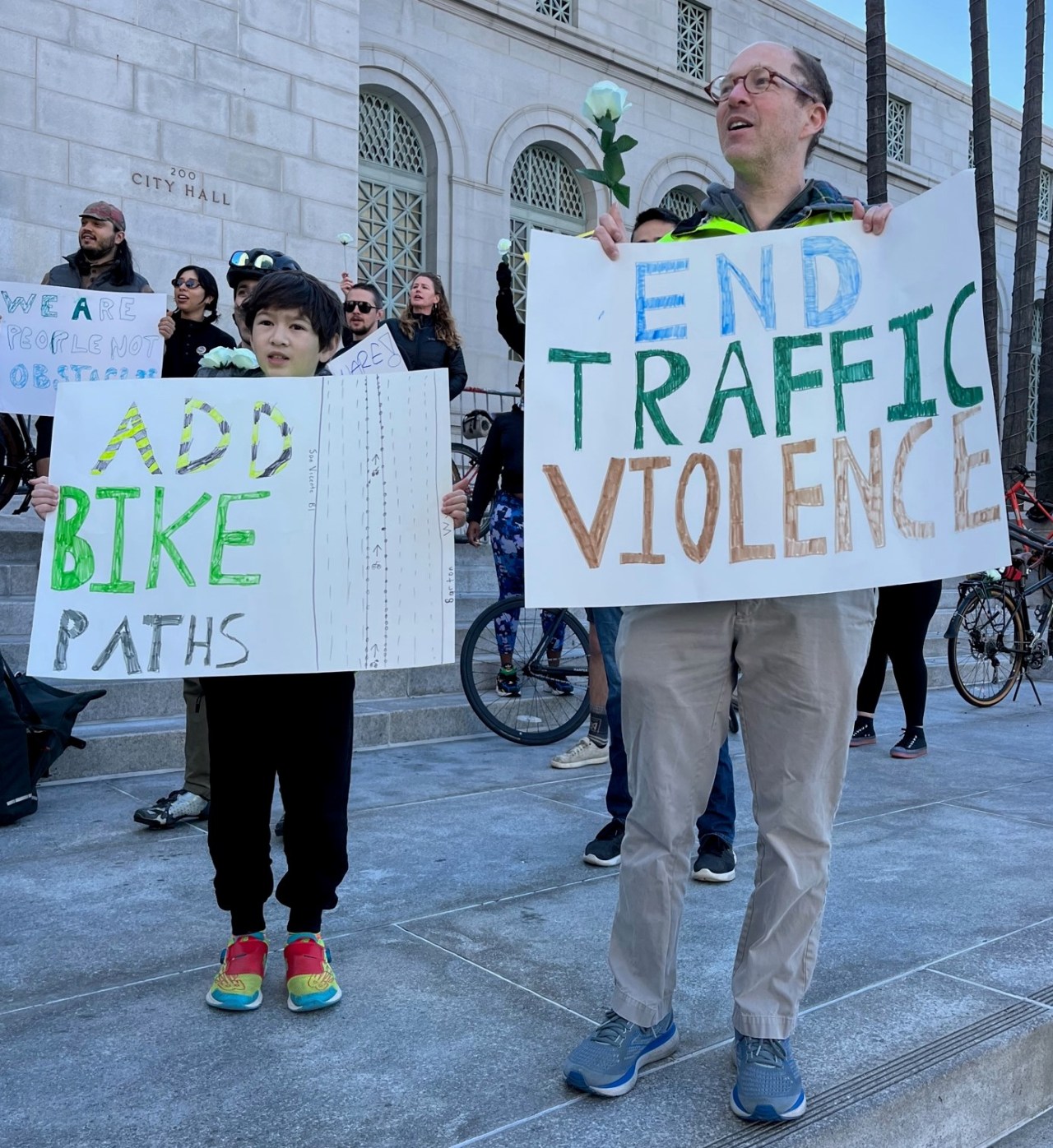 Protestors carrying signs for ending traffic violence and adding more bikeways